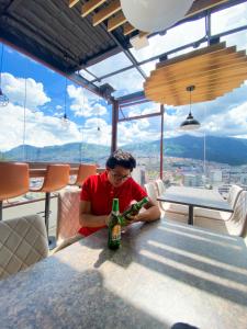 Hostal La Terraza في كيتو: رجل يجلس على طاولة مع زجاجة من النبيذ