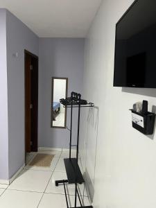 sala de estar con TV en una pared blanca en Chalé da Ana- com cozinha a 80 metros do Rio Preguiça en Barreirinhas