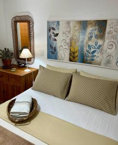 a bedroom with a white bed with a mirror at Suíte Girassol Cama & Café - Centro, Marechal Floriano-ES in Marechal Floriano