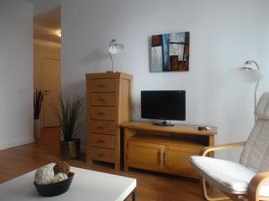 sala de estar con TV, silla y mesa en Málaga Apartamentos - Montaño, 18, en Málaga