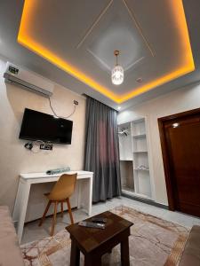 ein Wohnzimmer mit einem Sofa, einem Tisch und einem TV in der Unterkunft Hotel Eloued فندق الوادي in Tiksebt