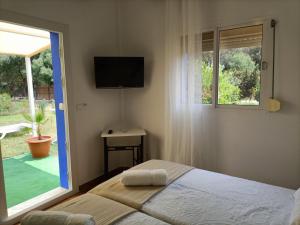 a bedroom with a bed and a window and a television at El Palomar Rooms Tarifa in Tarifa