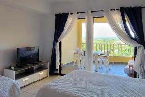 Portobello Palmanova, Palmas del Mar, Humacao, PR في هوماكاو: غرفة نوم بسرير وتلفزيون وطاولة مع كراسي