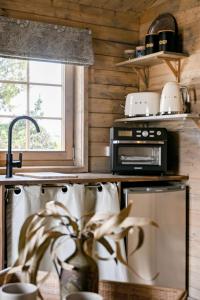 a kitchen with a stove and a microwave at Stylish Tiny Home with Fire Pit in Moss Vale in Moss Vale