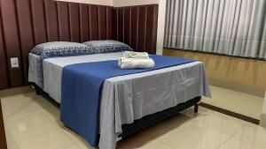 um quarto com uma cama com lençóis azuis e toalhas em Ap202 - Residencial Garves em Patos de Minas