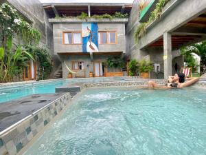 two people laying in a swimming pool at a hotel at Hermanos Perdidos Surf in Las Tunas