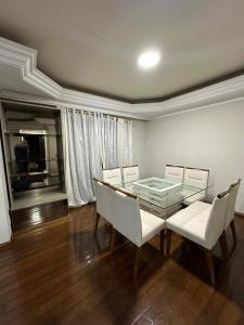 a dining room with a glass table and white chairs at Apartamentos Nadai 302 in Foz do Iguaçu +24 photos