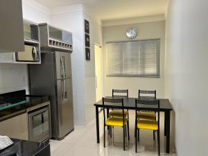 uma cozinha com uma mesa preta e cadeiras amarelas em Ap202 - Residencial Garves em Patos de Minas