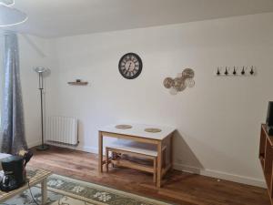 Zimmer mit einem Tisch und einer Uhr an der Wand in der Unterkunft Appartement saint ouen 45M2 in Saint-Ouen