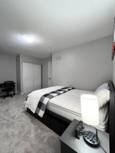 a bedroom with a bed and a table with a lamp at Room in Oshawa, 24/7 Security, Free Parking in Oshawa