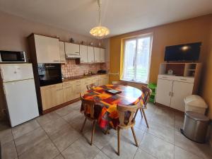 a kitchen with a table and a kitchen with a refrigerator at Gîte Parroy, 4 pièces, 6 personnes - FR-1-584-29 