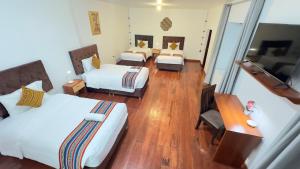 um quarto de hotel com três camas e uma secretária em Casona Liberty Inn em Cusco