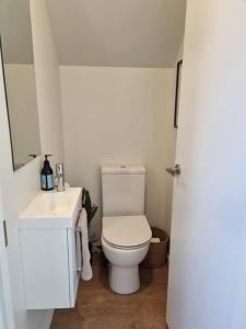 Un baño blanco con inodoro y lavabo. en Central Home with Internal Garage - Close to CBD!, en Christchurch