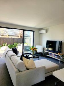 Una sala de estar con un sofá blanco y un televisor de pantalla plana. en Central Home with Internal Garage - Close to CBD!, en Christchurch
