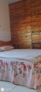 1 dormitorio con 1 cama con pared de madera en Pousada Shalon e Hostel Holly Land, en Santo Amaro