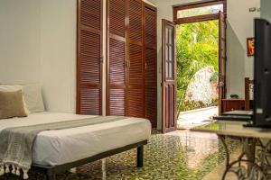 a bedroom with a bed and a sliding glass door at Casa Armadillo, colonial house with pool in Mérida +33 photos