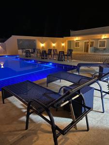uma piscina à noite com cadeiras e mesas em Condomínio Farol das Dunas em Santo Amaro