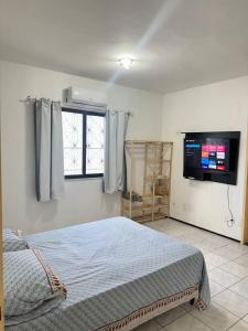 a bedroom with a bed and a flat screen tv at Ap no Derby com Garagem in Sobral