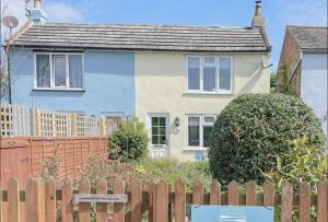 Aldringham的住宿－Knodishall - Newly renovated 2 bed holiday home, near Aldeburgh, Leiston and Thorpeness，木制围栏后面的蓝色和白色房子