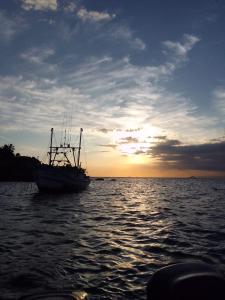 ein Boot, das bei Sonnenuntergang im Wasser sitzt in der Unterkunft Beautiful day suítes in Ilhabela