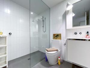 a white bathroom with a toilet and a shower at BPM Brighton APT with Garden LG1 in Melbourne +8 photos