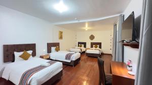 um quarto de hotel com duas camas e uma secretária e uma televisão em Casona Liberty Inn em Cusco