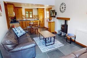 a living room with a leather couch and a table at CROYDE THATCHERS HIDEAWAY 2 Bedrooms in Croyde