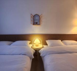 a room with two beds and a table with a lamp at Stay Banwoldang in Daegu
