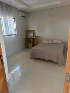 a bedroom with a bed in a white room at Apartamento da Pâm - em frente ao clube cantão in Pontes e Lacerda
