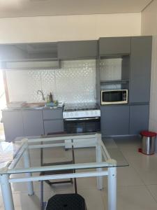 a blue kitchen with a glass table in it at Apartamento da Pâm - em frente ao clube cantão in Pontes e Lacerda