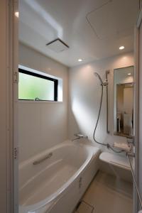 a white bathroom with a tub and a toilet at Kihaku in Kutchan