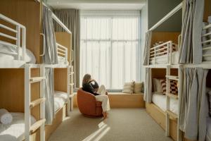 a woman sitting in a chair in a room with bunk beds at Drifter Christchurch in Christchurch