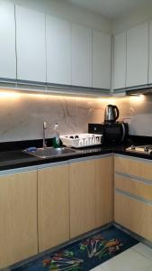 une cuisine avec des armoires blanches, un évier et une cuisinière dans l'établissement Iloilo Condominiums, à Iloilo