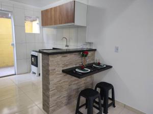 a kitchen with a counter with two stools and a sink at Loft Outono Centro Histórico in Paraty