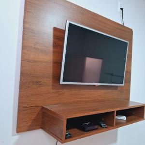 uma televisão de ecrã plano num centro de entretenimento em madeira em Flat ideal para familia e grupos de amigos proximo ao aeroporto e rodoviária em Palmas