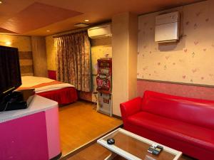 a living room with a red couch and a bed at Himeji Baby Kiss (Adult Only) in Himeji
