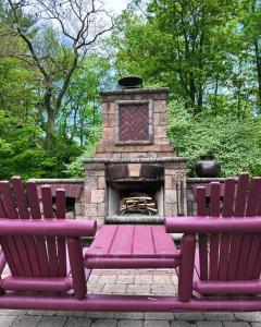 dos bancos púrpuras sentados junto a una chimenea de piedra en 37 Oak Ridge House, en Wellsboro