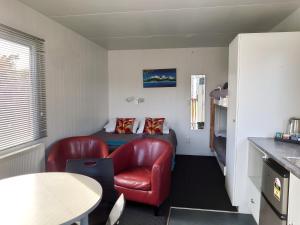 um pequeno quarto com uma cadeira vermelha e uma cama em Taupo Debretts Spa Resort em Taupo