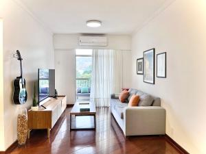 a living room with a couch and a guitar at Jacarepaguá Residence - Quarto em apartamento in Rio de Janeiro