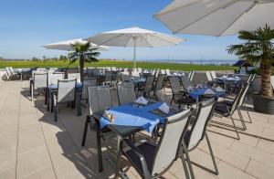a group of tables and chairs with umbrellas at Seemöwe Wellnesshotel Swiss Quality in Güttingen
