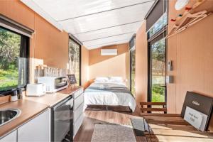 um quarto com uma cama e uma cozinha com um lavatório em Yengo Tiny House em Broke