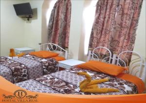a room with two beds with orange pillows at HOSTAL VILLA.REAL in Quito