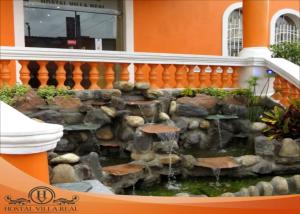 a fish pond in front of a building at HOSTAL VILLA.REAL in Quito +8 photos