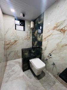 a bathroom with a white toilet and marble walls at B&B Villa in Daman