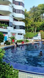 BINANCE @ Sri Sayang Beach Resort في باتو فيرينغي: مجموعة أشخاص في مسبح بجوار مبنى