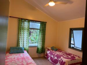 ラロトンガ島にあるRaina Holiday Accommodationのベッドルーム1室(ベッド2台、窓付)