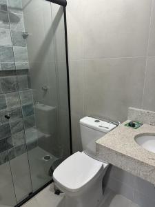 a bathroom with a toilet and a shower and a sink at Condomínio Mares do Sul in Salinópolis