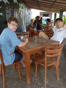 eine Gruppe von Menschen, die an einem Holztisch sitzen in der Unterkunft Negombo Royal Villa by Hotel Oviniru in Negombo