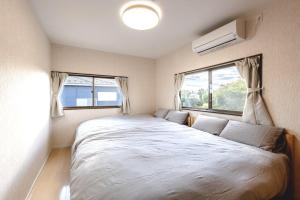 a bedroom with a large bed and two windows at ANGO Kujukuri II in Katakai