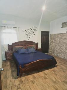 um quarto com uma grande cama de madeira com lençóis azuis em Garden house, 1 km de pradera chiquimula em Chiquimula